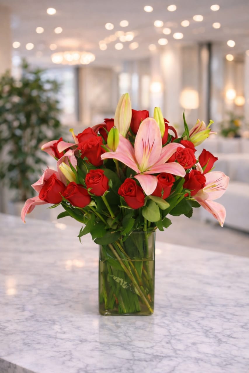 This is a bouquet of pink lilies and red roses arranged in a clear glass vase.